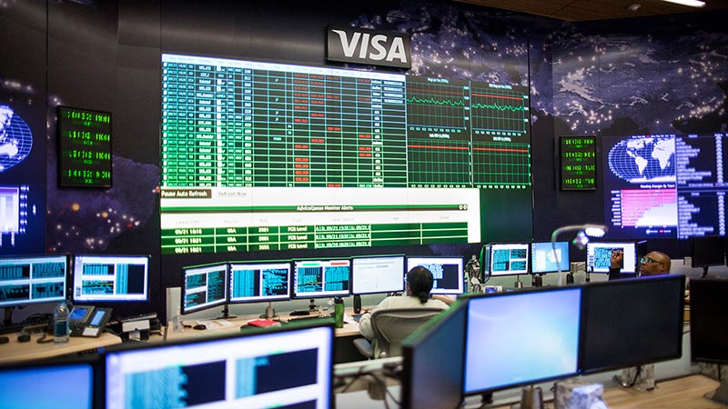A Visa employee monitors multiple screens and displays full of data.